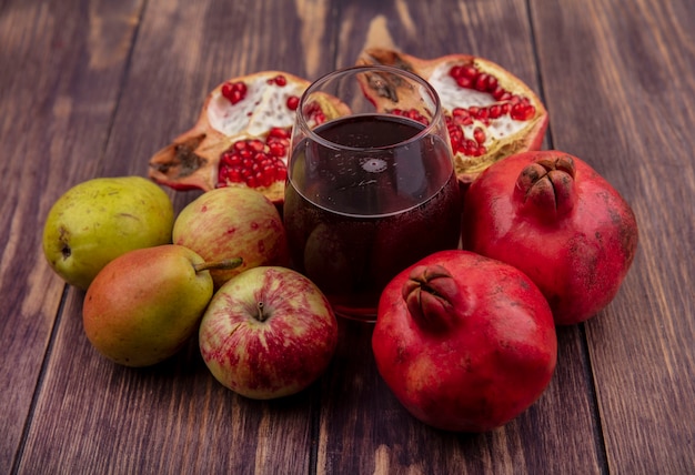 Front view glass of pomegranate juice with pomegranates apples and pears on wood wall