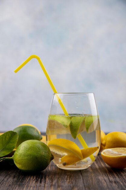 Front view glass of water with lemon slices with lime and yellow straw