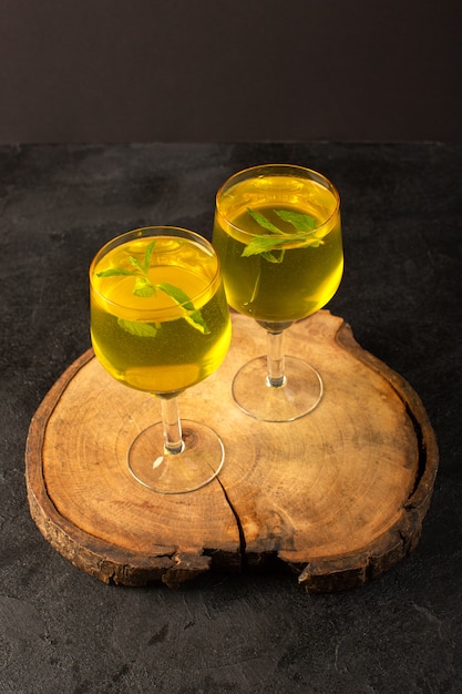 Free photo a front view glasses with juice lemon juice inside transparent glasses on the brown wooden desk