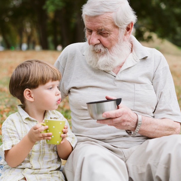 Free photo front view grandpa and grandson drinking tea