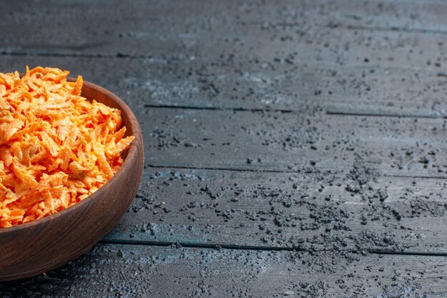 Front view grated carrot salad inside plate on dark-blue rustic desk health salad color ripe diet vegetables