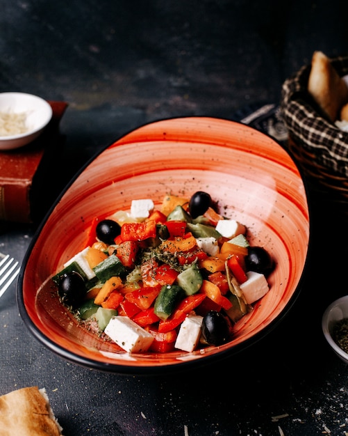 Front view greece salad with olives tomatoes white cheese and cucumbers inside black plate on the dark floor