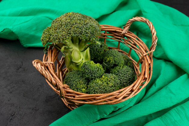 front view green broccoli fresh ripe inside basket on the green tissue and grey floor