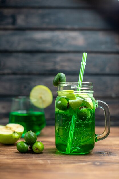 Front view green feijoa juice inside can with green apples on the wooden desk bar fruit color drink photo cocktail