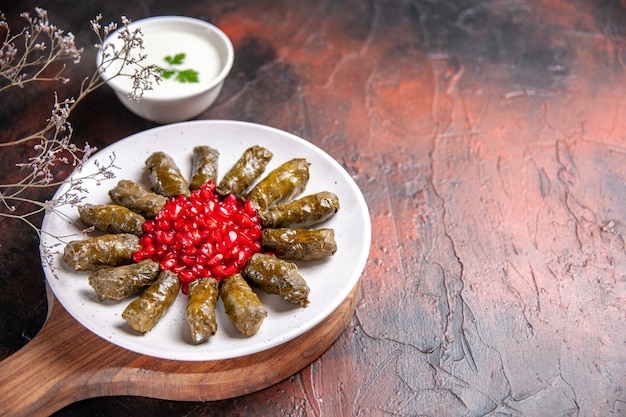 Front view of green leaf dolma with pomegranates on dark surface