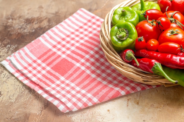 Front view green and red peppers hot peppers tomatoes in wicker basket kitchen towel on amber