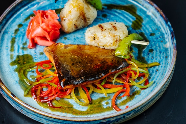 Front view grilled fish with sauce and bell pepper on a plate