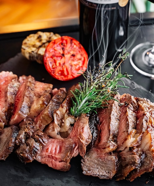 Front view grilled meat with rosemary and a slice of tomato on the board