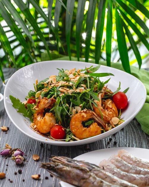 Front view grins salad with shrimps nuts arugula and cherry tomatoes