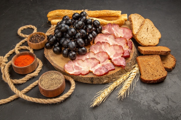 Front view ham slices with grapes seasonings and bread slices on dark snack color photo meat food meal