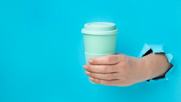 Free photo front view hand holding reusable cup with copy space