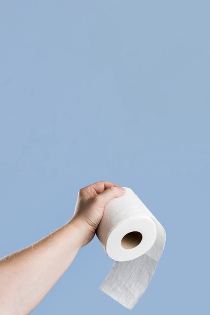 Front view of hand holding toilet paper with copy space