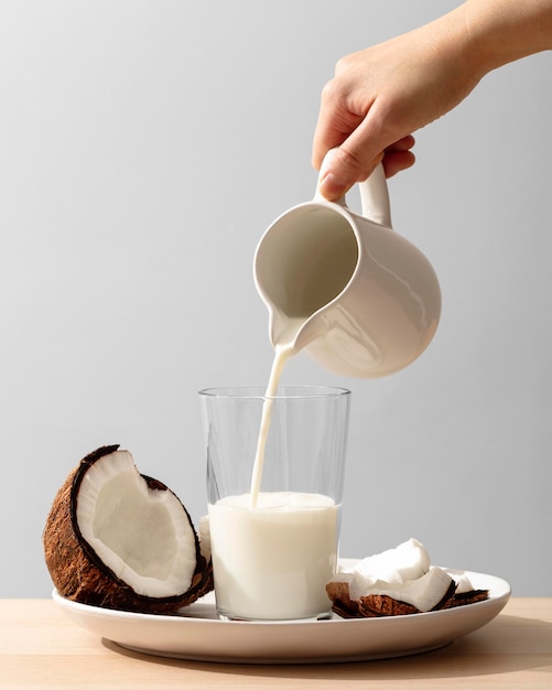 Free Photo front view of hand pouring coconut milk in glass