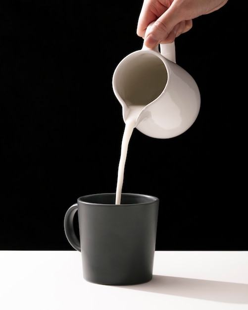 Front view of hand pouring milk into mug