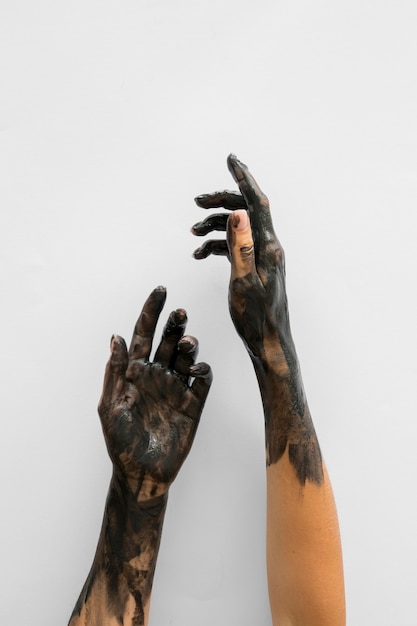 Free photo front view of hands covered in black paint with copy space