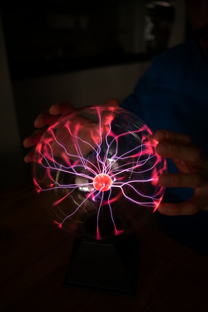 Free Photo front view hands interacting  with a plasma ball