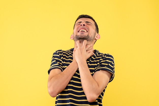 Free photo front view handsome male in black and white striped t-shirt holding throat on yellow isolated background