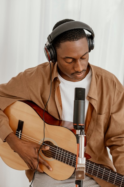 Free Photo front view of handsome male musician at home playing guitar