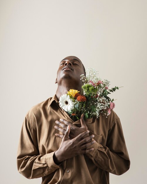 Front view of handsome man posing with bouquet of flowers