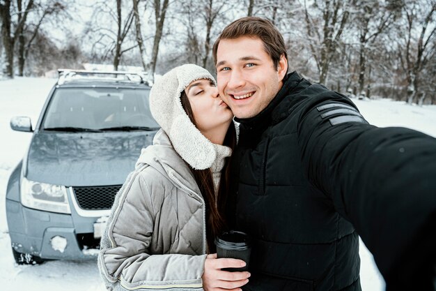 Front view of happy couple taking selfie while on a road trip