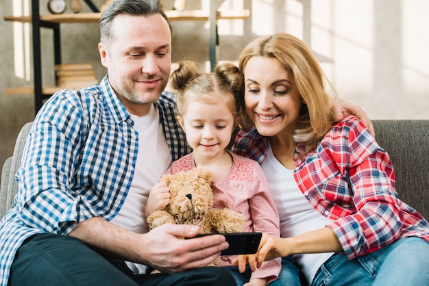 Front view of happy family looking in mobile phone