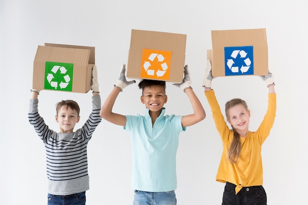 Front view happy kids holding recycling boxes