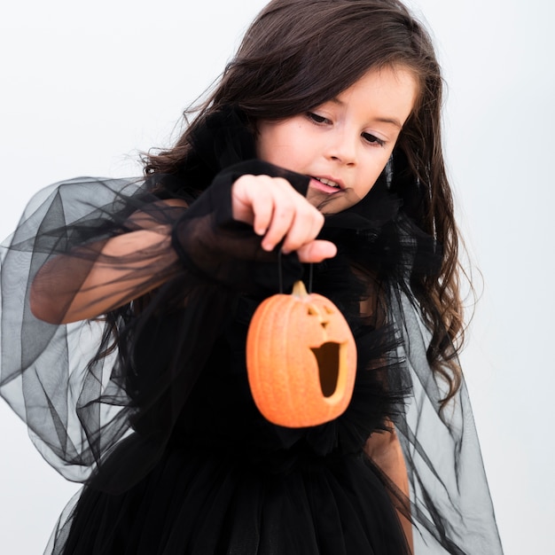 Free photo front view happy little girl holding a pumpkin