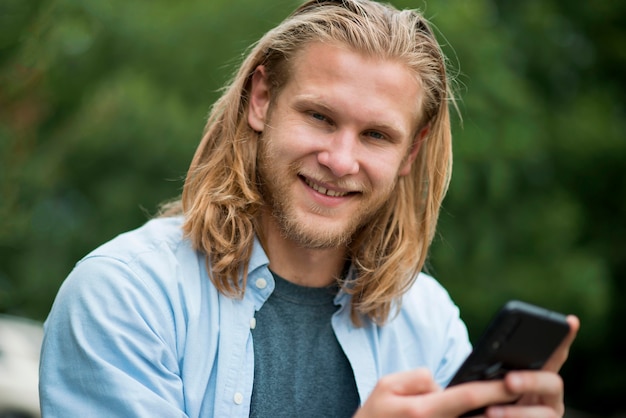 Free photo front view of happy man outdoors with phone