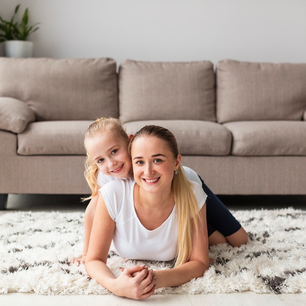 Front view of happy mother and daughter posing at home