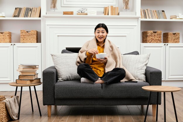 Front view happy woman eating popcorn and sitting on the couch