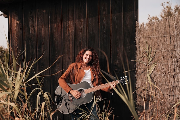 Free photo front view happy woman playing a guitar