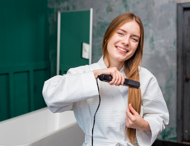 Free photo front view of happy woman straightening her hair