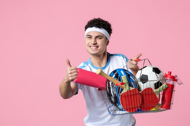 Free photo front view happy young male in sport clothes with basket full of sport things