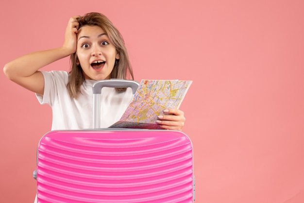 Free photo front view of happy young woman with pink suitcase holding map