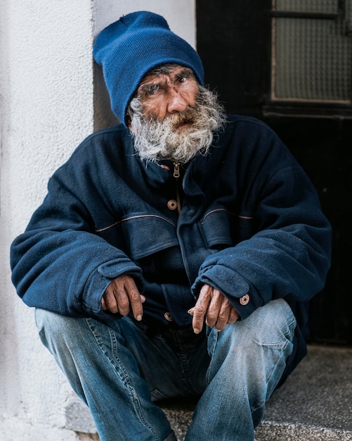 Front view of homeless man with beard on doorstep