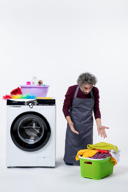 Front view housekeeper man standing on knee looking at laundry basket on white background