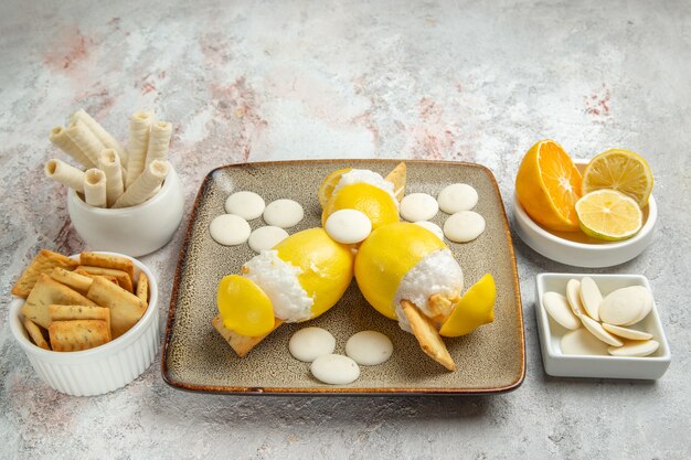 Front view iced lemons with candies and cookies on white table juice cocktail fruits drink