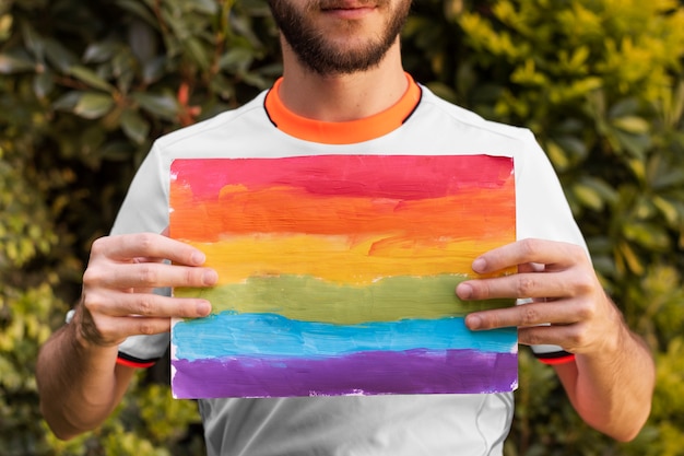 Free photo front view individual holding rainbow colored paper