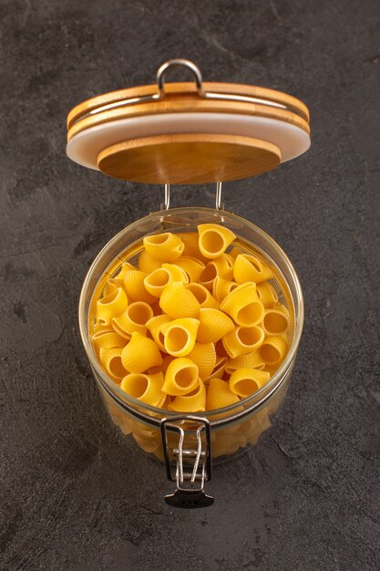 A front view italian dry pasta yellow raw inside bowl isolated on the dark