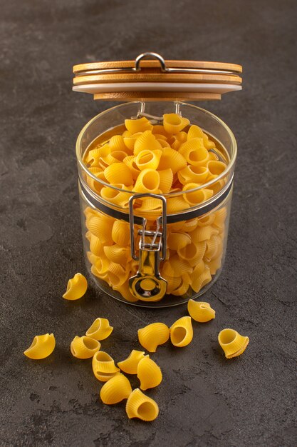 A front view italian dry pasta yellow raw inside bowl isolated on the dark