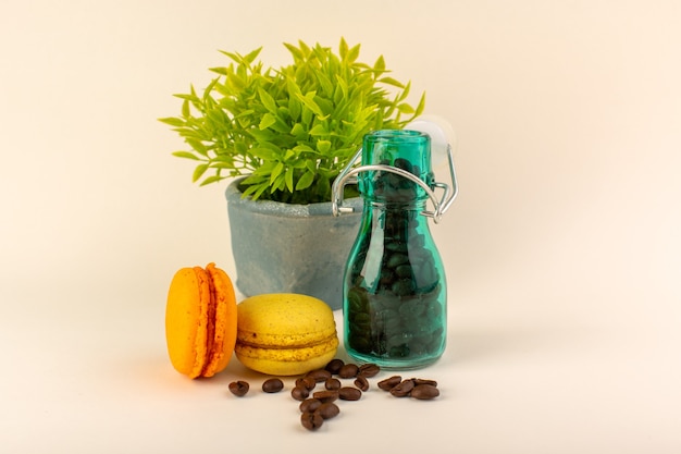 Free Photo a front view jar with coffee french macarons and green plant on the pink table coffee color flower seed