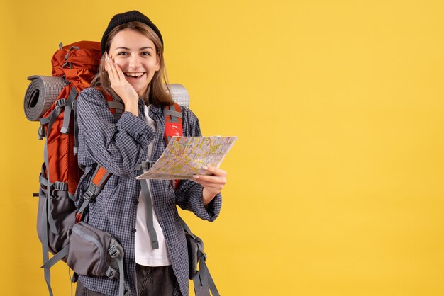 Front view of joyful young traveller with backpack holding map