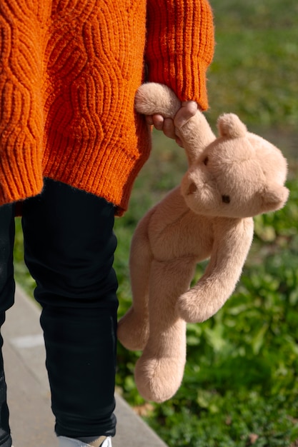 Front view kid holding teddy bear outdoors