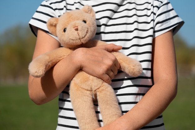 Front view kid holding teddy bear outdoors