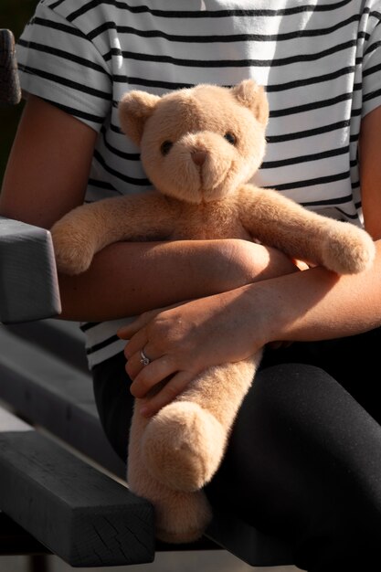 Front view kid holding teddy bear outdoors