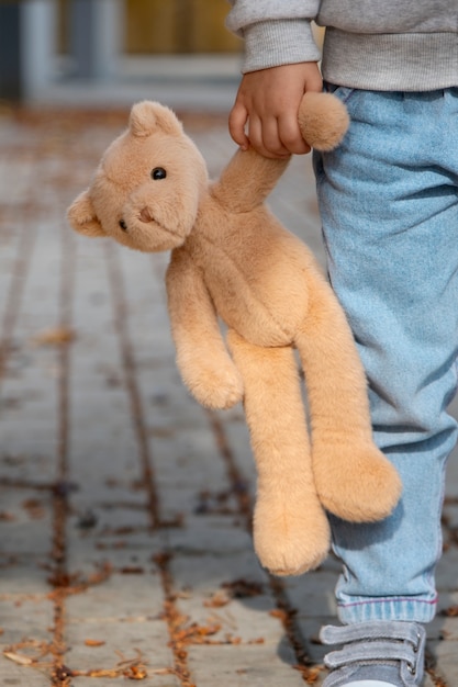 Front view kid holding teddy bear outdoors