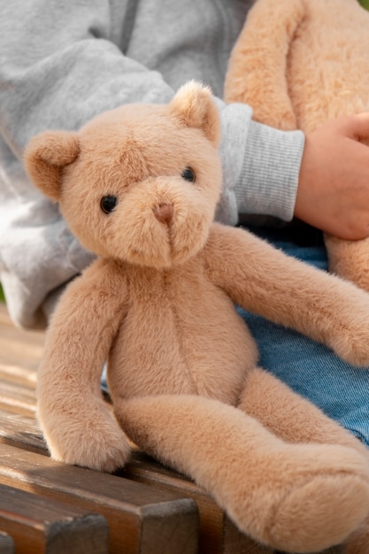 Front view kid holding teddy bear outdoors