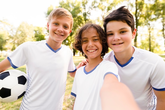 Front view kids in football sportswear taking a selfie