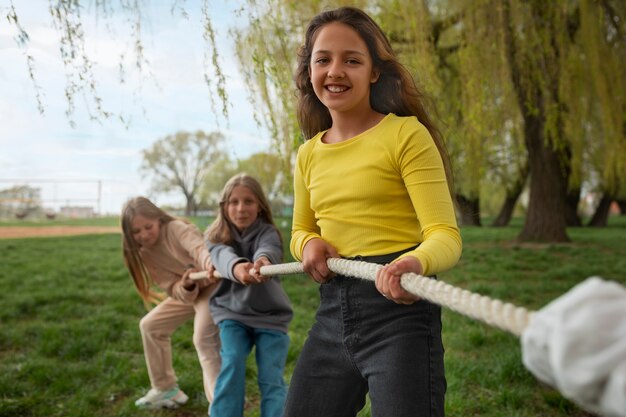 Front view kids playing tug-of-war in the park