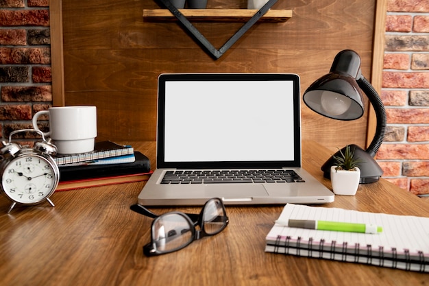 Front view of laptop and lamp on wooden office workspace